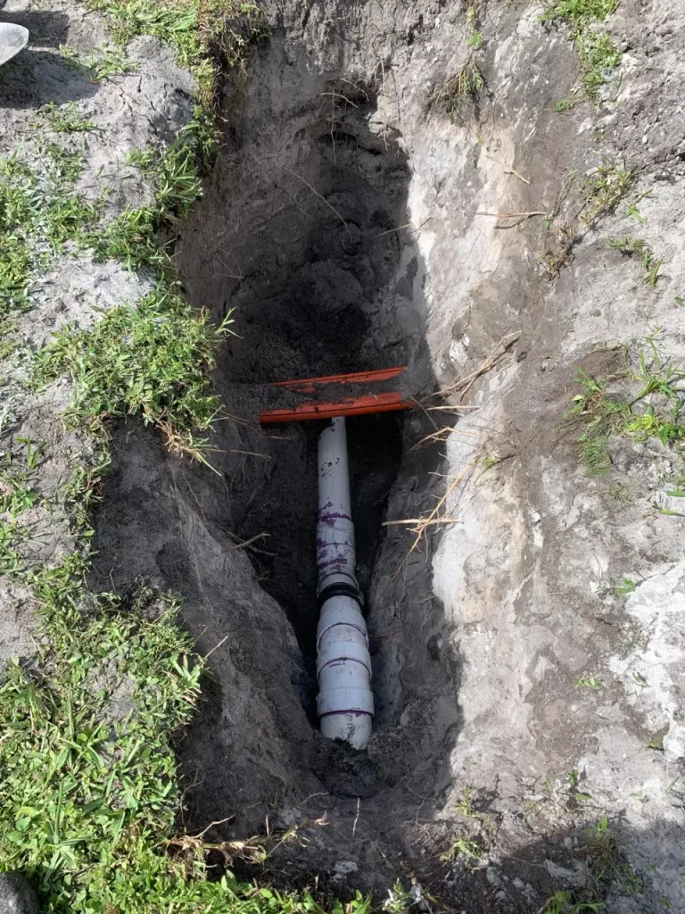 Deep excavation with vertical PVC drain pipe prepared for waterproofing and clamping ring installation.